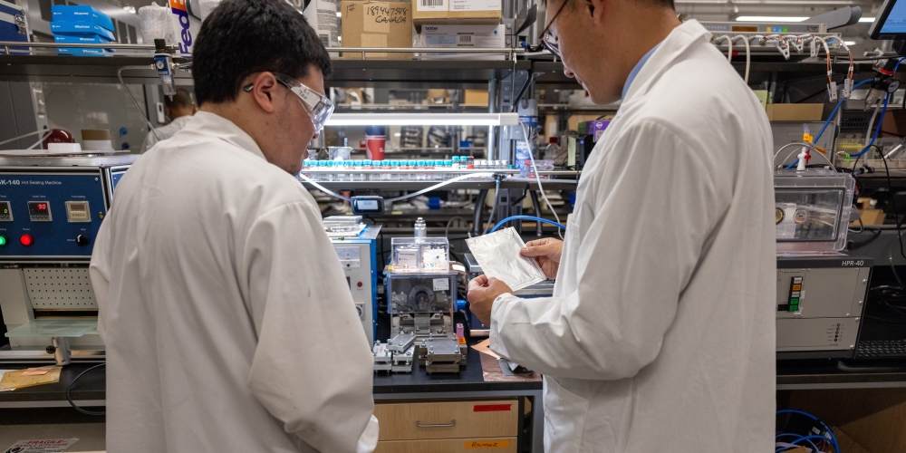 Two researchers examining a device in the lab.