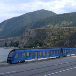 An artist rendering of a light rail train running in front of Okanagan Lake.