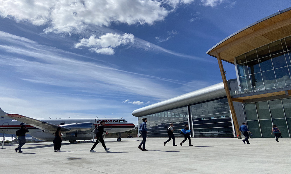 Students walk across an airport tarmac into a hangar. 